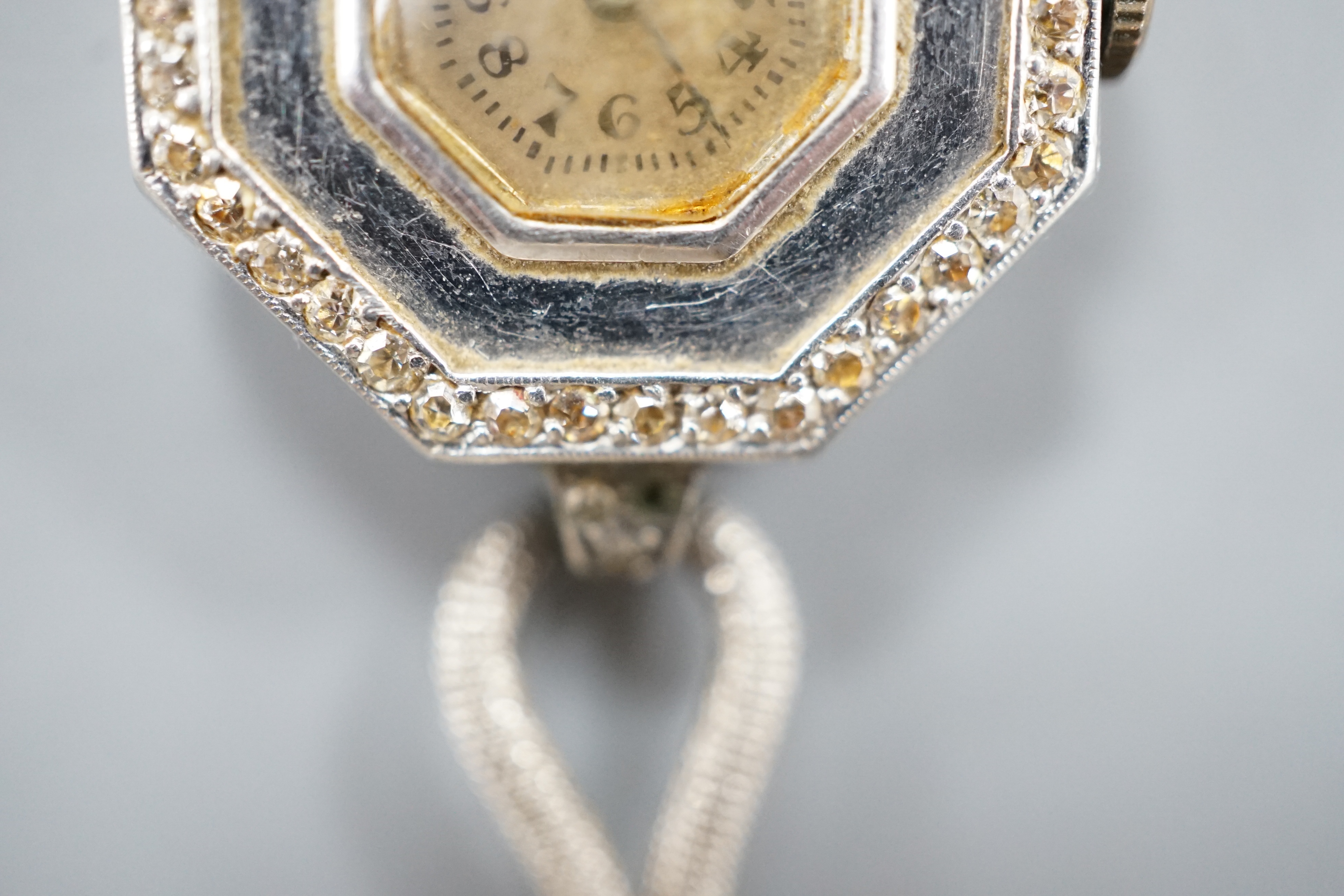 A lady's early 20th century white metal and diamond chip set manual wind octagonal cocktail watch, on a white metal twin strand mesh bracelet, gross 27.4 grams.